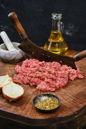 Making fresh raw minced meat with vintage chopping knife on wooden log
