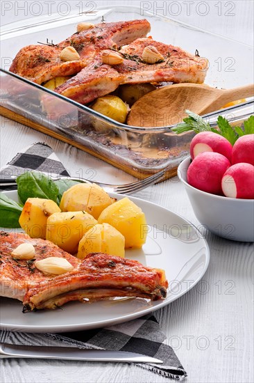 Steak with bone and potato baked in oven in a roasting pan with garlic and thyme