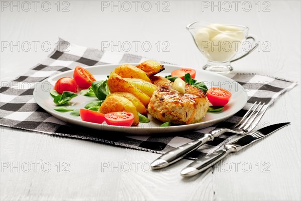 Fried chicken cutlet with potato slices served with tomato cherry and corn salad. Traditional belorussian food