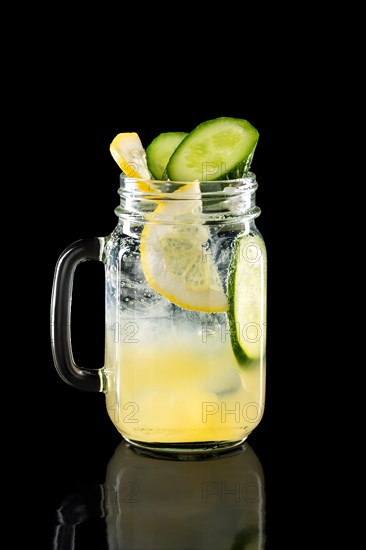 Cold fruit lemonade in mason jar isolated on black background