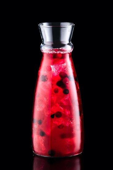 Cold sangria with forrest berries in a jar isolated on black background