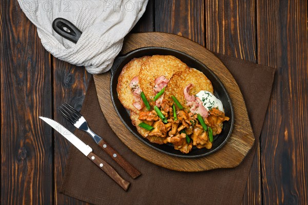 Top view of potato pancakes with chanterelles and pork in cast iron skillet