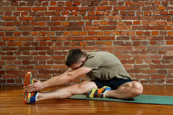 Young male cyclist athlete training and doing workout on gym mat. Fitness workout