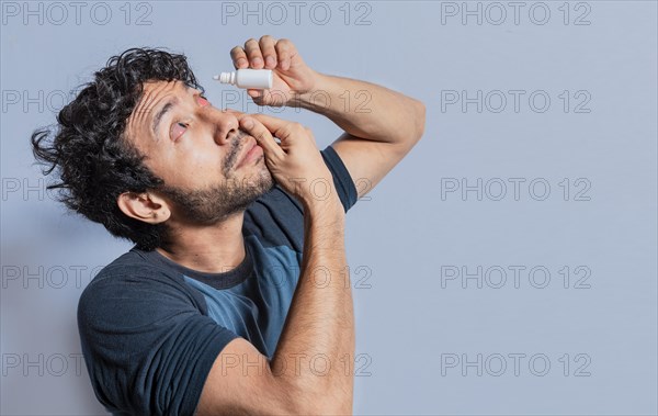 Person applying dropper to irritated eye. People applying refreshing drops to irritated eye. Man putting a dropper in his eye isolated. Man with irritated eye applying drops with a dropper