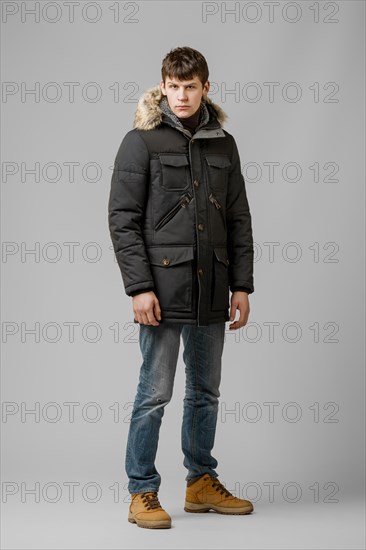 Full length portrait of handsome man in warm winter coat posing in studio