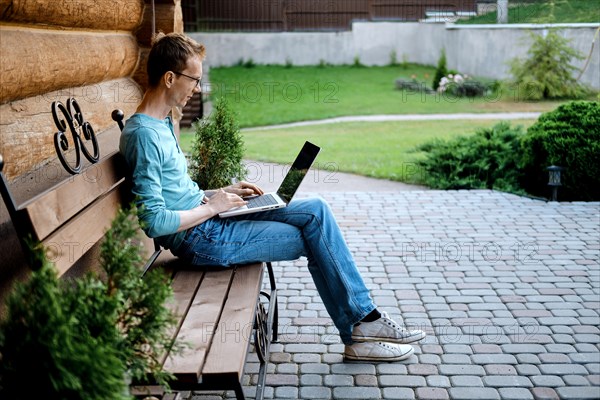 Middle aged man sitting on bench at the backyard of his country house