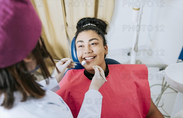 Close up of female dentist doing dental checkup to smiling patient
