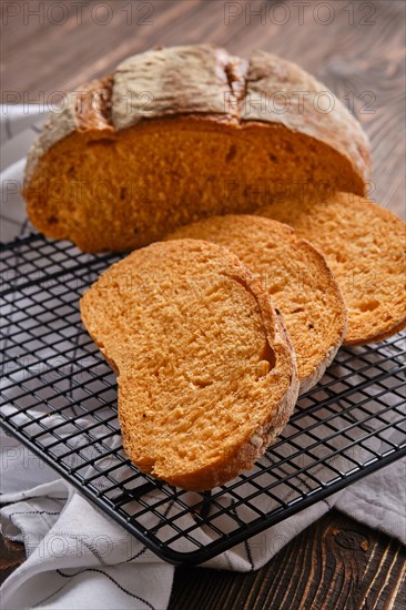 Closeup view of artisan whole grain tomato wheat bread cut on slices on wooden table