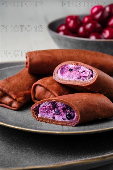 Closeup view of thin chocolate pancakes stuffed with curd
