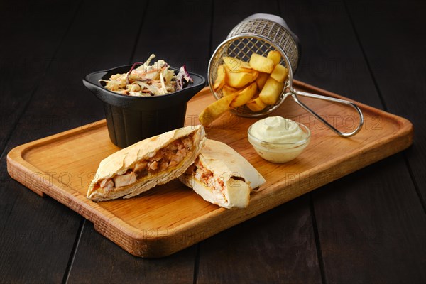 Tostada with chicken fillet served with cabbage salad and american fries on wooden tray