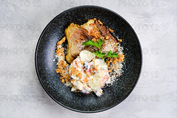 Top view of pickled cucumber with boiled potato and olives served with fried pork belly slices on a plate