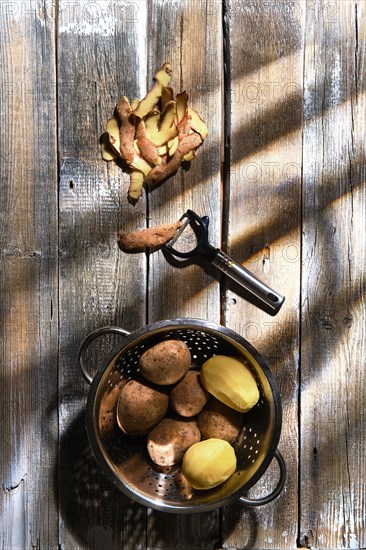 Top view of fresh potatoes and potato peelings with a knife on a table