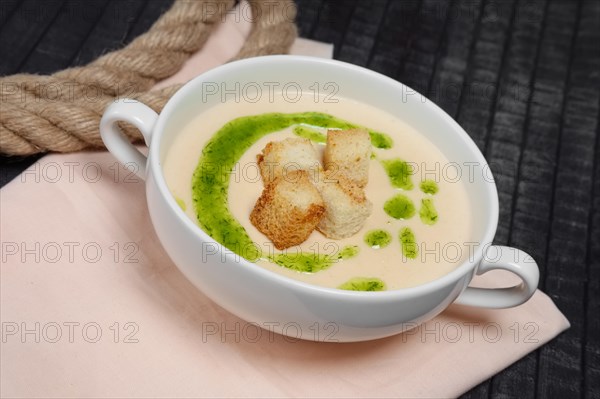 Creamy soup puree in white bowl and small pieces of fried bread toasts