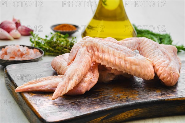 Closeup view of fresh uncooked chicken wings on wooden cutting board ready for cooking