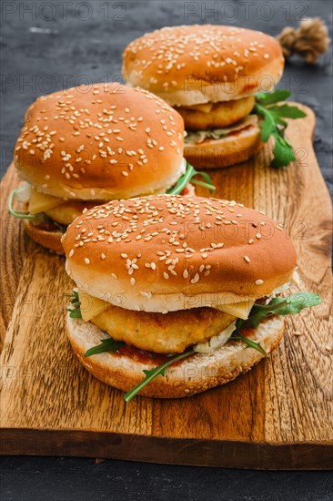 Homemade burger with chicken cutlet on long wooden board