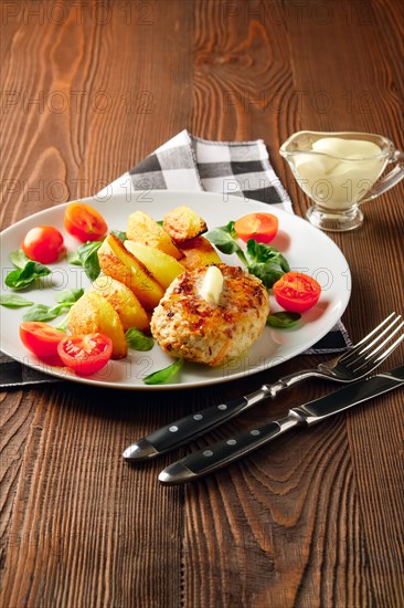 Fried chicken cutlet with potato slices served with tomato cherry and corn salad. Traditional belorussian food