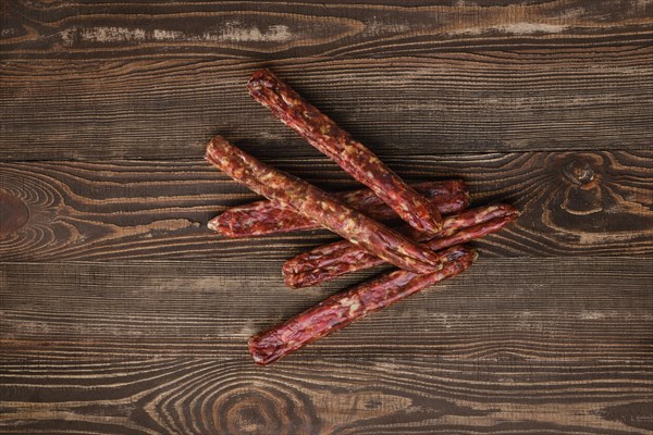 Overhead view of dried jerked deer and pork sausage on wooden background