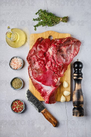 Overhead view of raw fresh deer boneless ham with spice and herb over concrete background