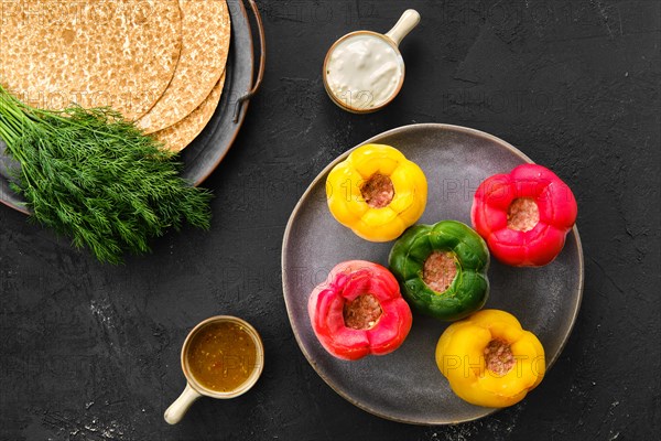 Top view of colorful bell pepper stuffed with meat and rice on black background