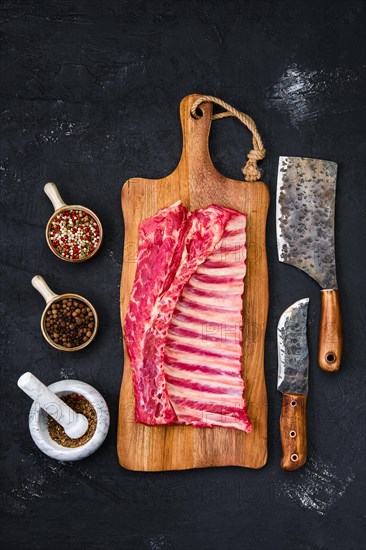 Fresh raw rack of lamb on wooden cutting board with herbs and seasoning