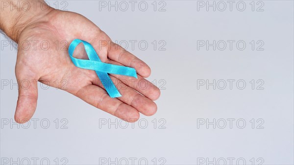Close up hand holding blue ribbon