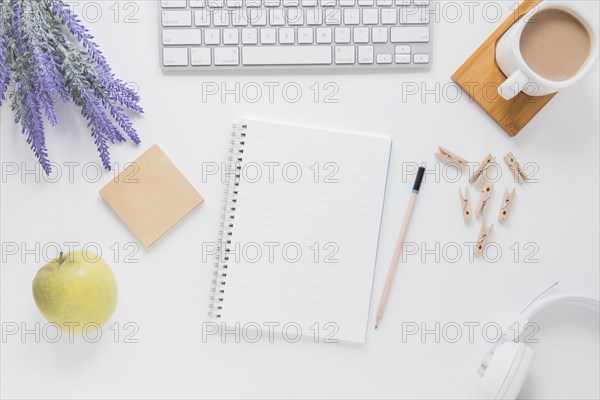 Opened notebook near stationery white table with gadgets coffee cup
