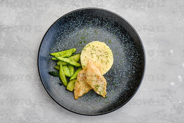 Top view of fried zander fillet in breading with mashed potatoe and pickled cucumber