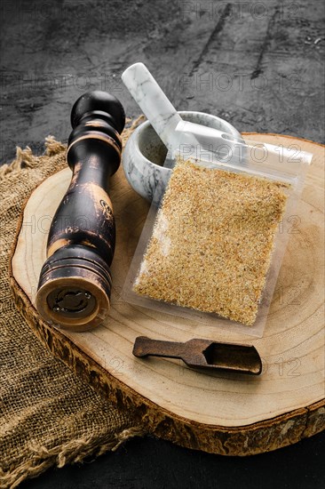 Wooden cross section with garlic in plastic package and stone mortar and mill