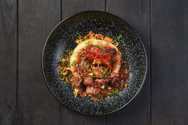 Overhead view of beef goulash with bacon and mashed potato on a table