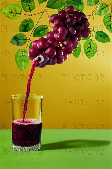Pouring juice in glass from a bunch of grapes