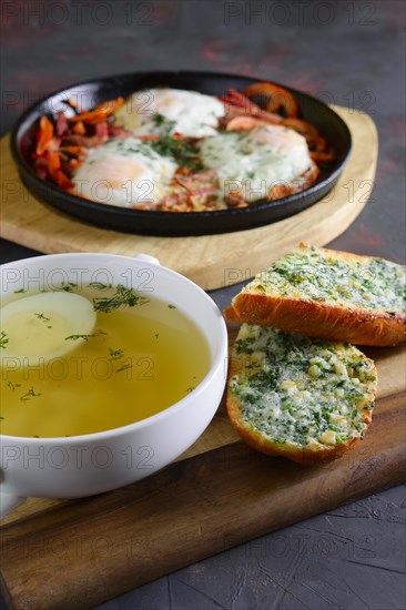 Clear chicken broth with egg served with toasts
