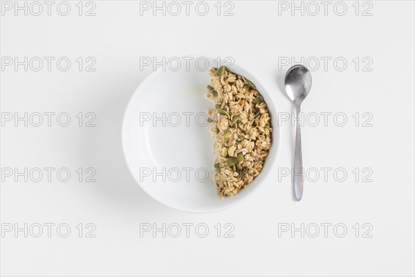 Granola with pumpkin seeds white bowl spoon white background