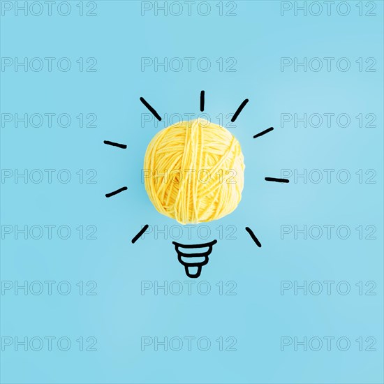 Light bulb made with yellow ball yarn blue backdrop