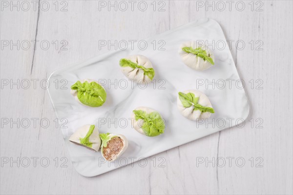 Top view of frozen dumplings stuffed with pork meat and provencal herbs on marble serving plate
