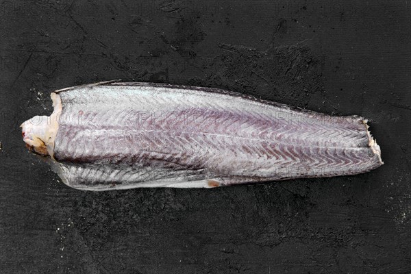 Frozen raw hake carcass on wooden table