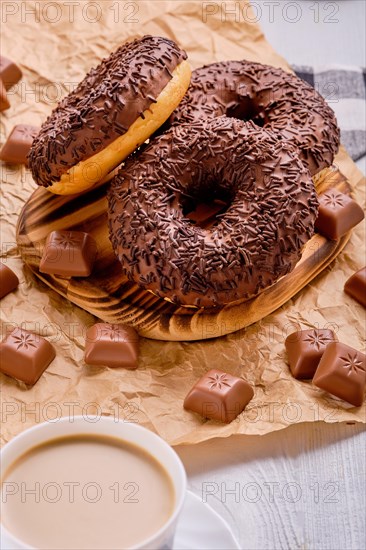 Overhead view of chocolate donuts on bright wooden background