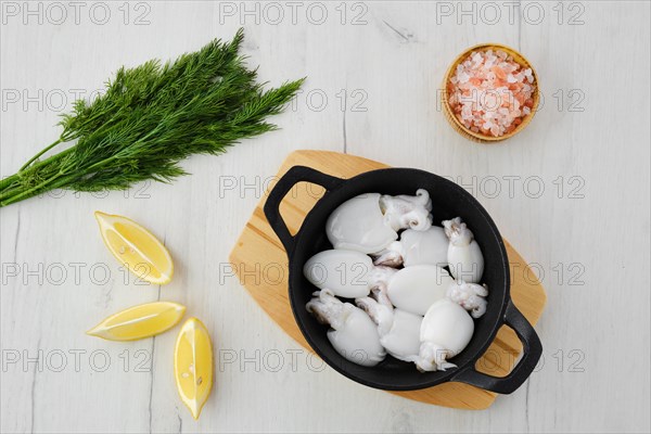 Overhead view of baby cuttlefish in cast iron skillet with dill
