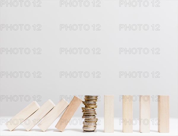 Pile coins stopping fallen wooden pieces front view