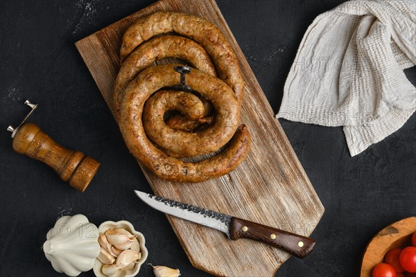 Horse meat sausage with garlic rolled on wooden cutting board