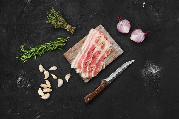 Overhead view of slices of pork bacon on wooden cutting board