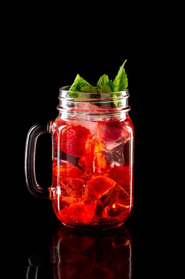 Cold fruit lemonade in mason jar isolated on black background