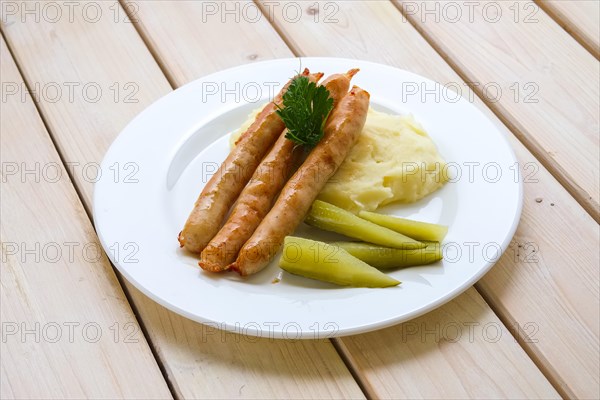 Fried sausage with mashed potato and pickled cucumber