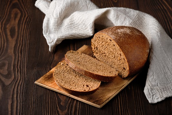 Freshly baked sliced brown bread on rustic wooden table