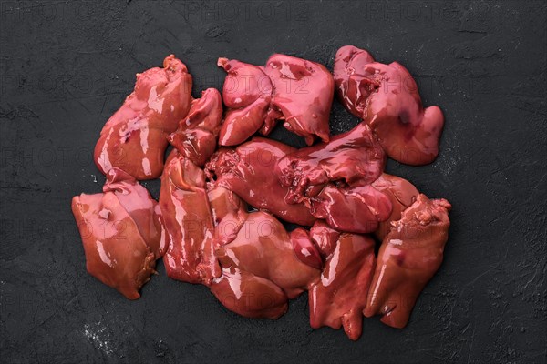 Top view of raw duck liver on black concrete background