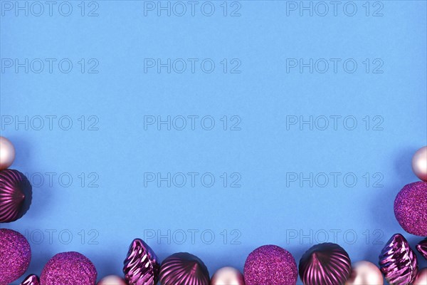 Seasonal Christmas background with violet and pink tree baubles at bottom and empty copy space with light blue background at top