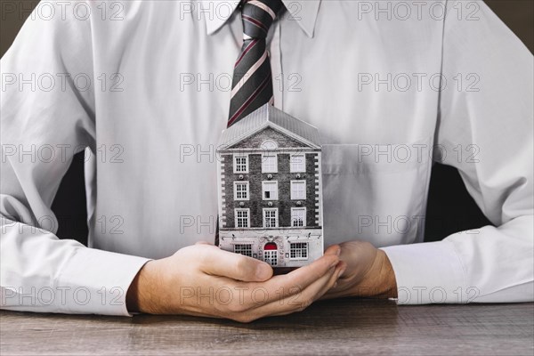 Man holding miniature house hands