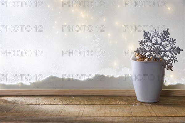 Mug with toy snowflake wood table near bank snow fairy lights