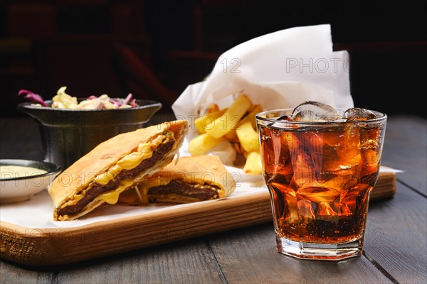 Glass of cola with ice with tortilla and fried potato on background