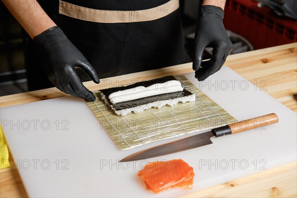 Hands of chef making salmon rolls