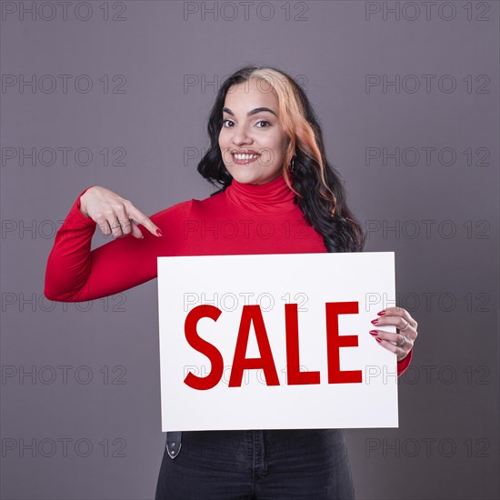 Beautiful woman pointing at a Sale sign. Commercial concept. Commerce